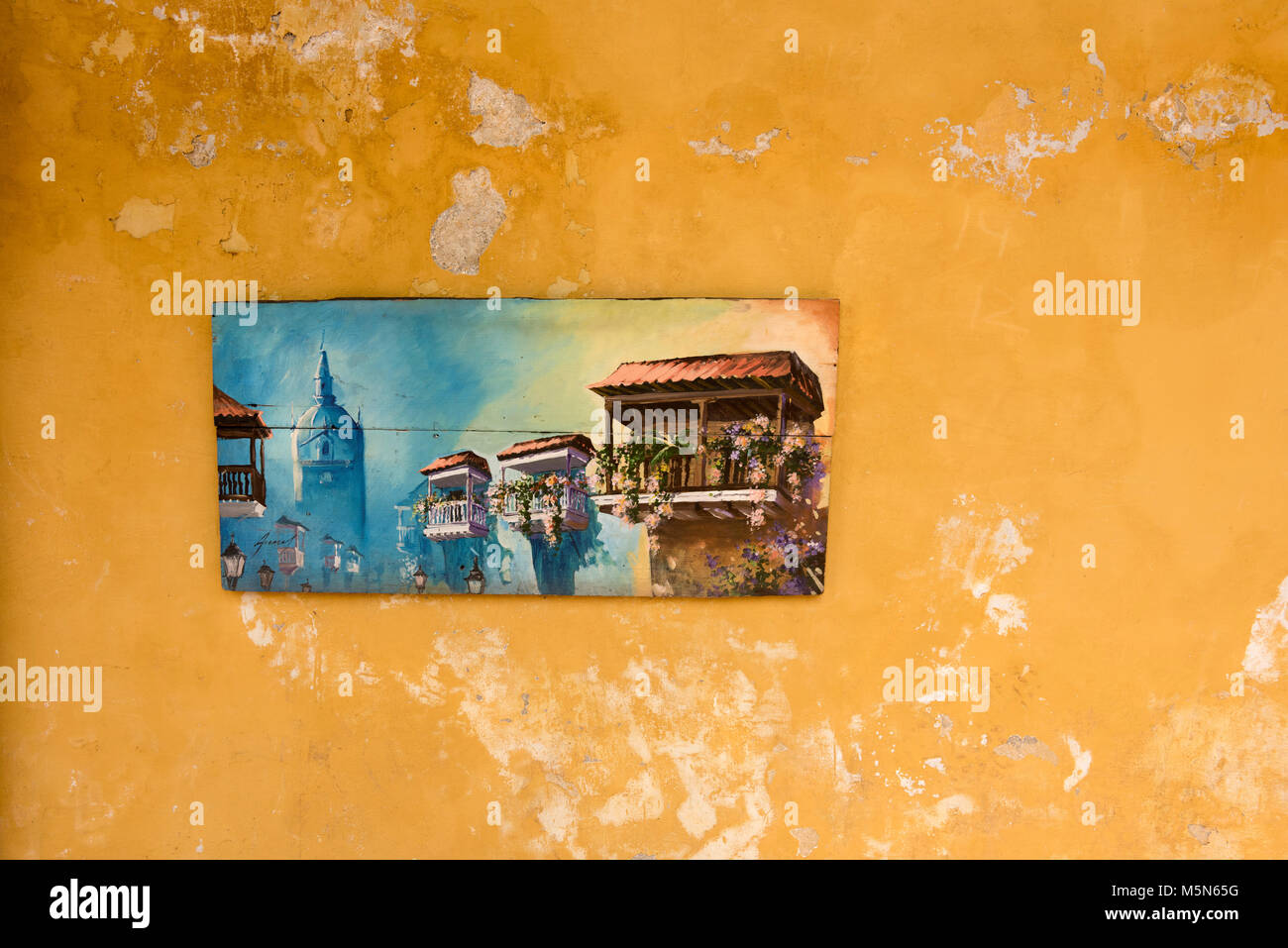 A picture of a street scene in Cartagena Coombia hanging on a distressd looking wall with flaking paint Stock Photo