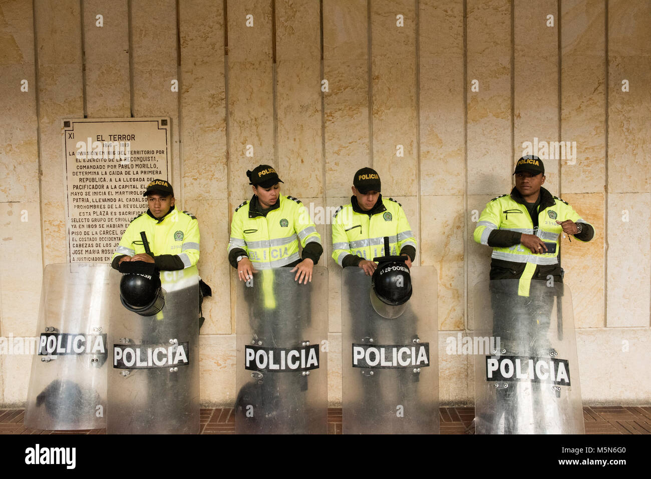 Police with riot gear rest outside municipal buildings in Simon Bolivar Square, Colombia Stock Photo