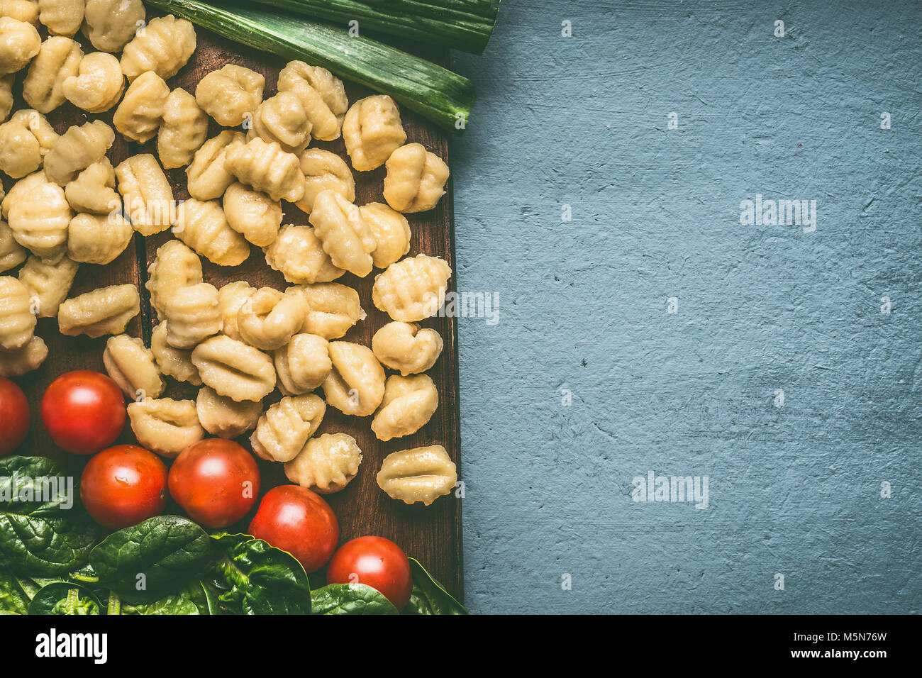 Close up of potato gnocchi with vegetarian cooking ingredients on rustic table with copy space, top view Stock Photo