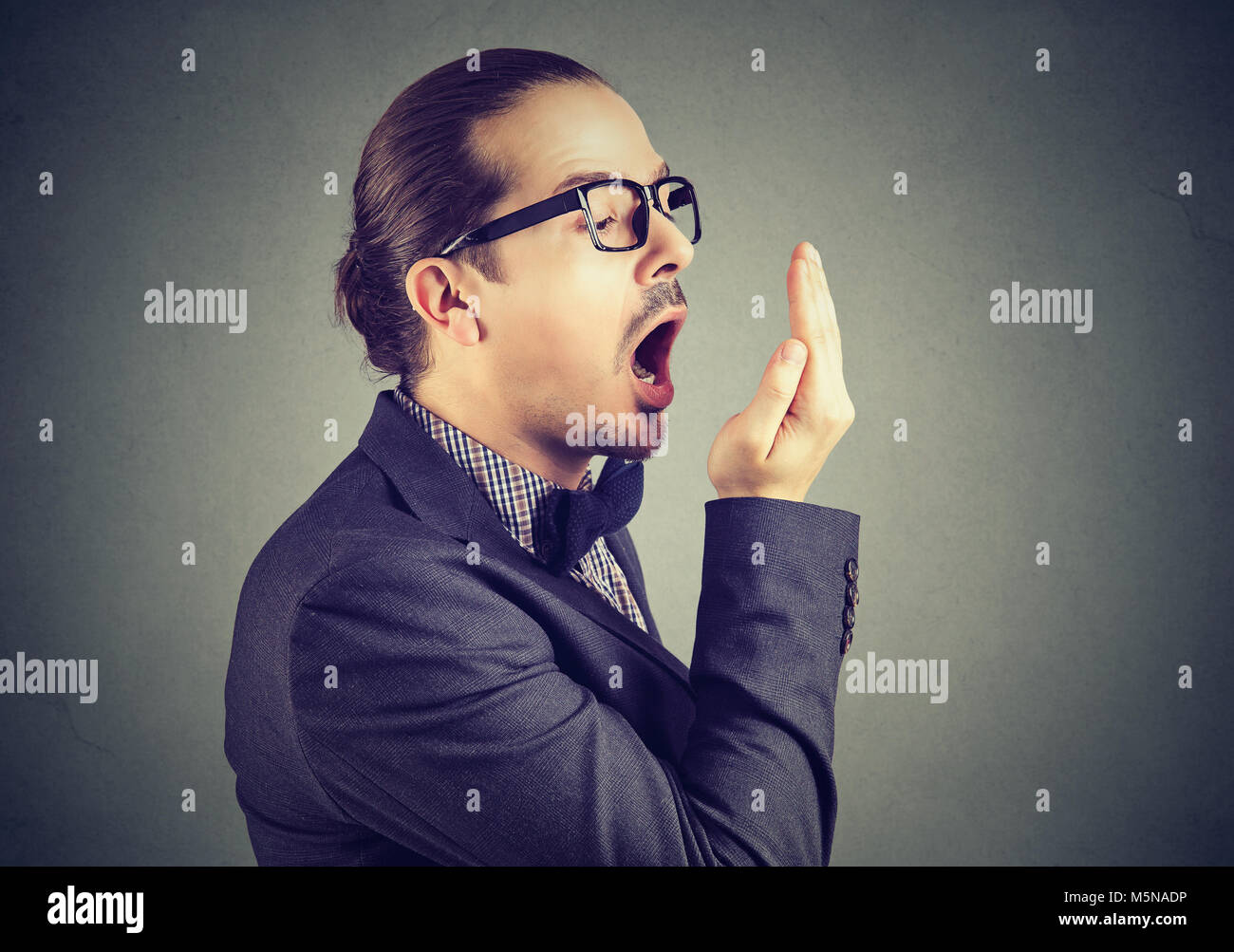 Young man checking his breath with hand test gesture. Stock Photo