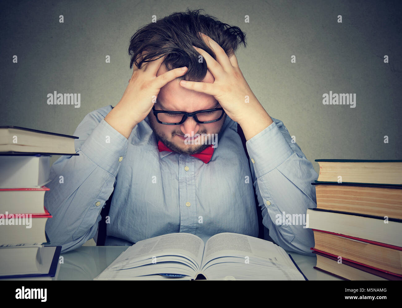 Stressed out student young man with desperate expression looking at his books Stock Photo