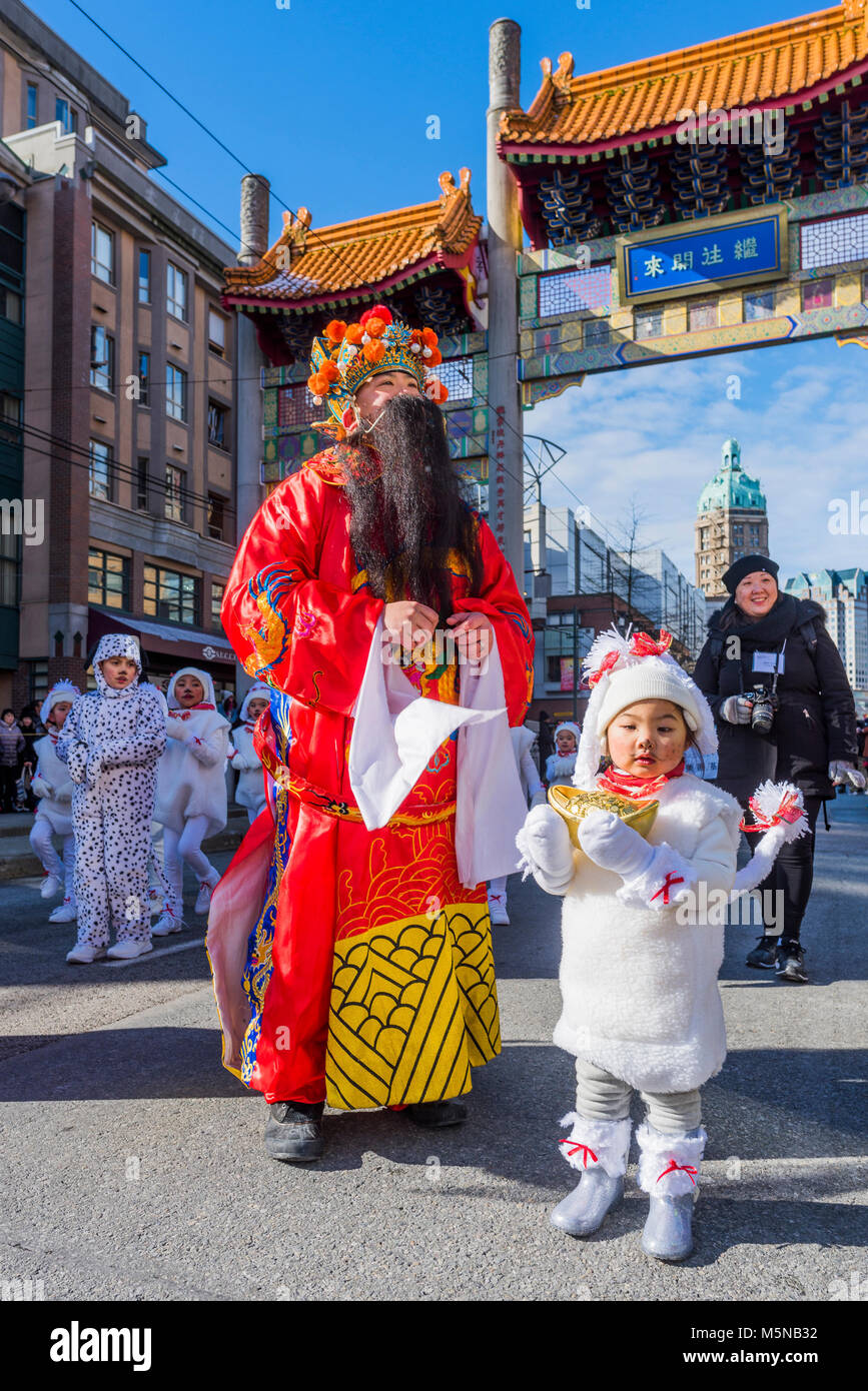 A performer dressed as Caishen, the Chinese god of wealth, prosperity, good fortune,  and little girl as a dog, Chinese Lunar New Year Parade, Chinato Stock Photo