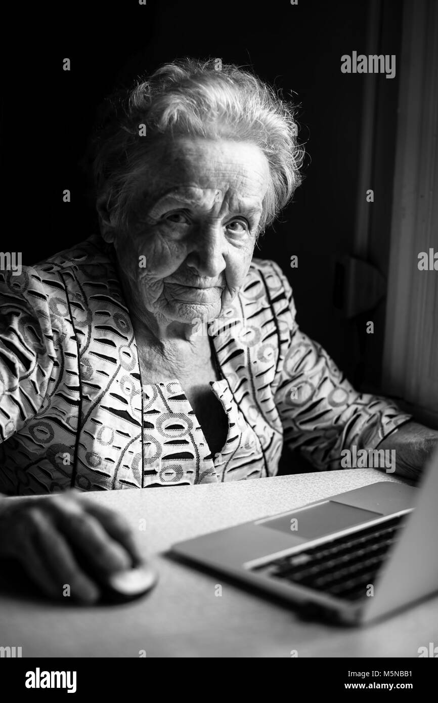 Elderly woman sitting with laptop. Black and white portrait. Stock Photo