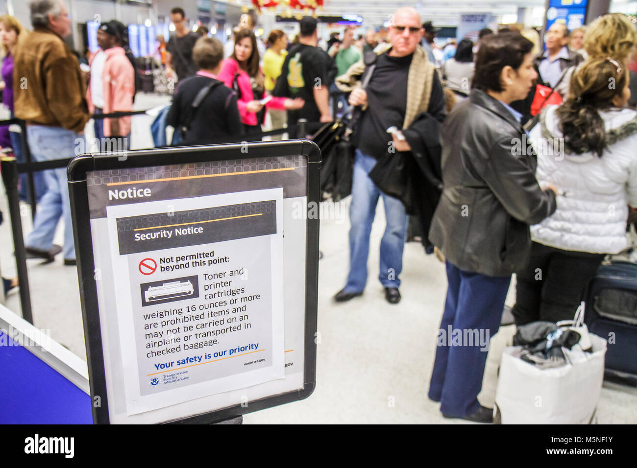 Miami Florida International Airport,gate security TSA passengers line queue,waiting warning sign notice prohibited items Stock Photo