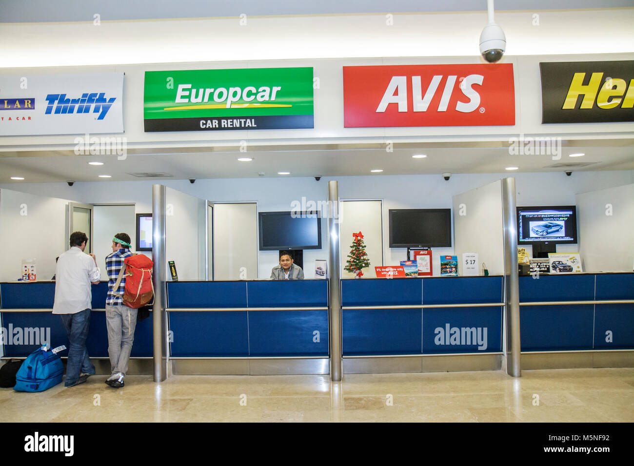 Cancun Mexico,Mexican,Cancun International Airport,rental car,counter,brands,Hispanic man men male adult adults,Avis,Hertz,Thrifty,Europcar,counter,re Stock Photo