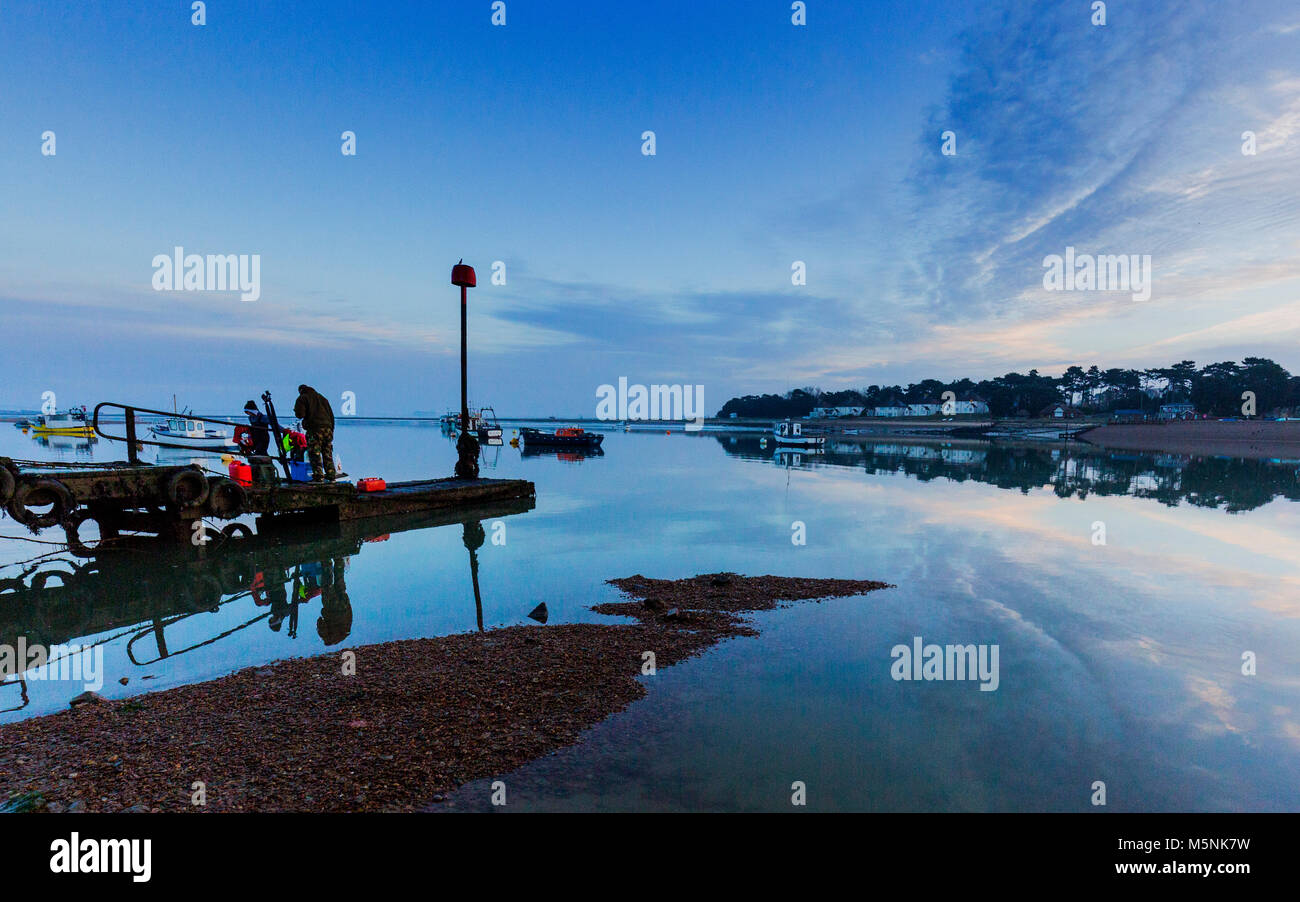 Two fisherman waiting for the boat to collect them from the jetty at Felixstowe Ferry in Suffolk, England. Stock Photo