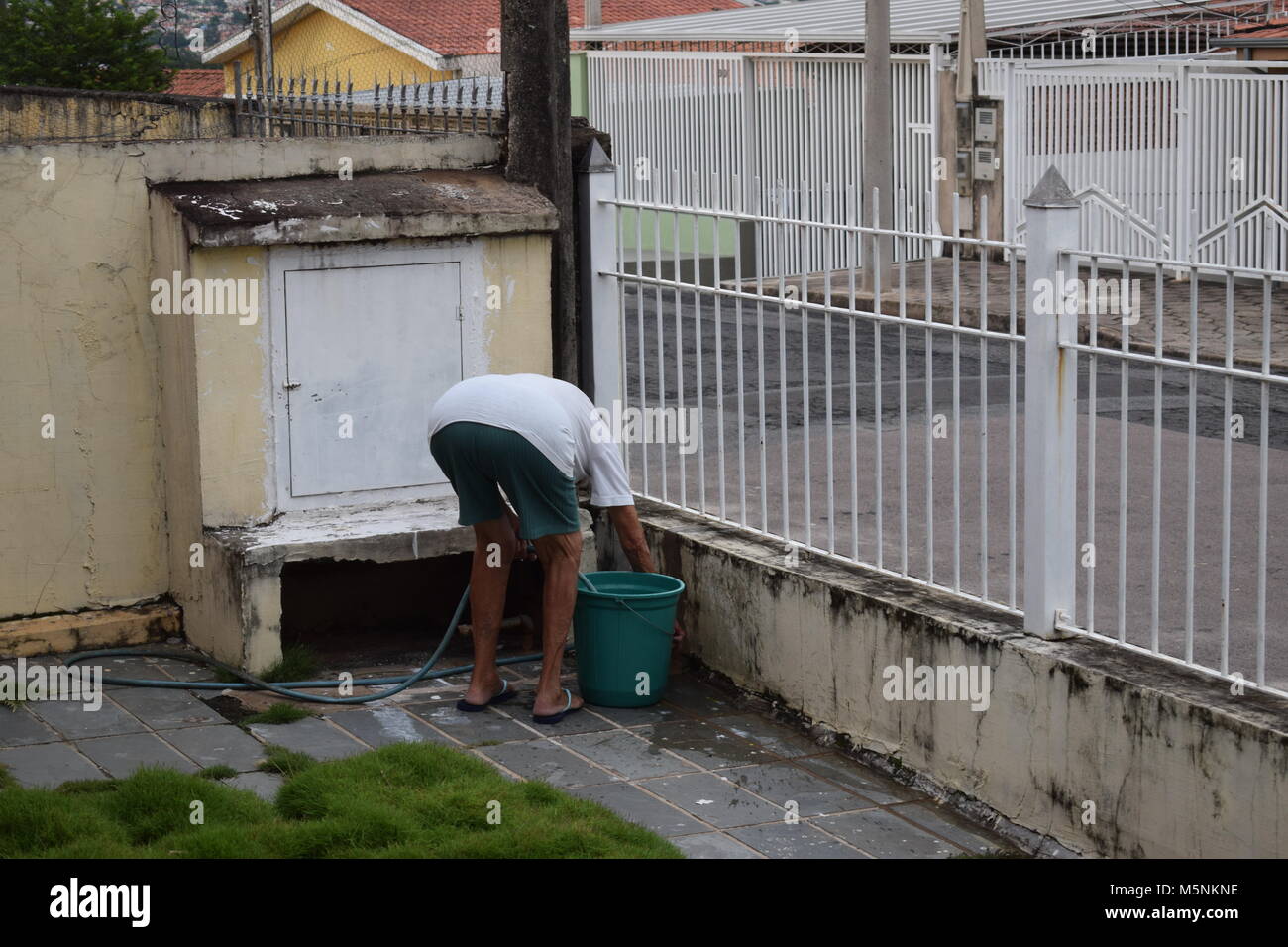 Woman filling bucket with hose Stock Photo Alamy