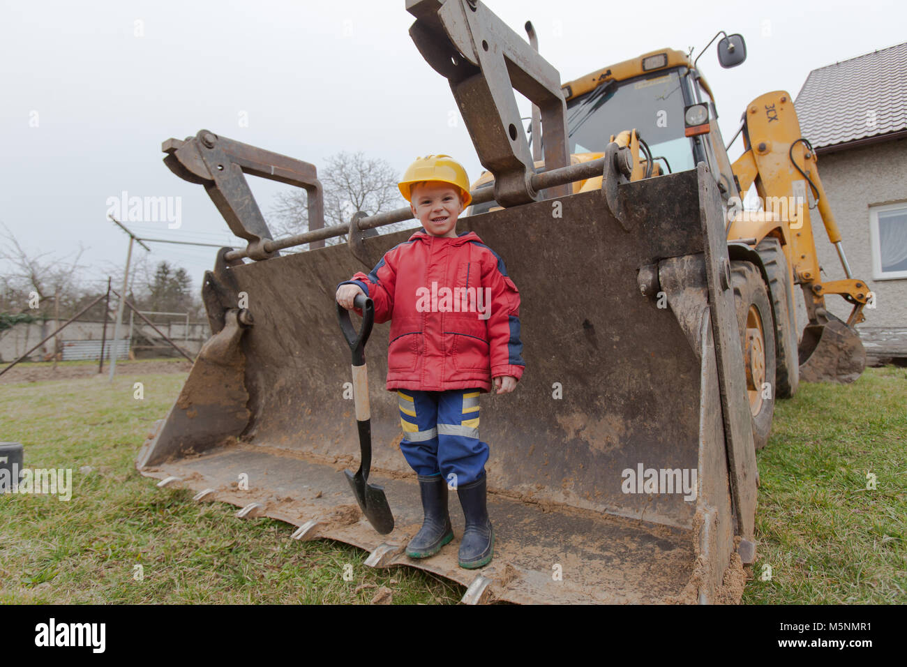 Little boy with a spade helps parents during the construction of the ...