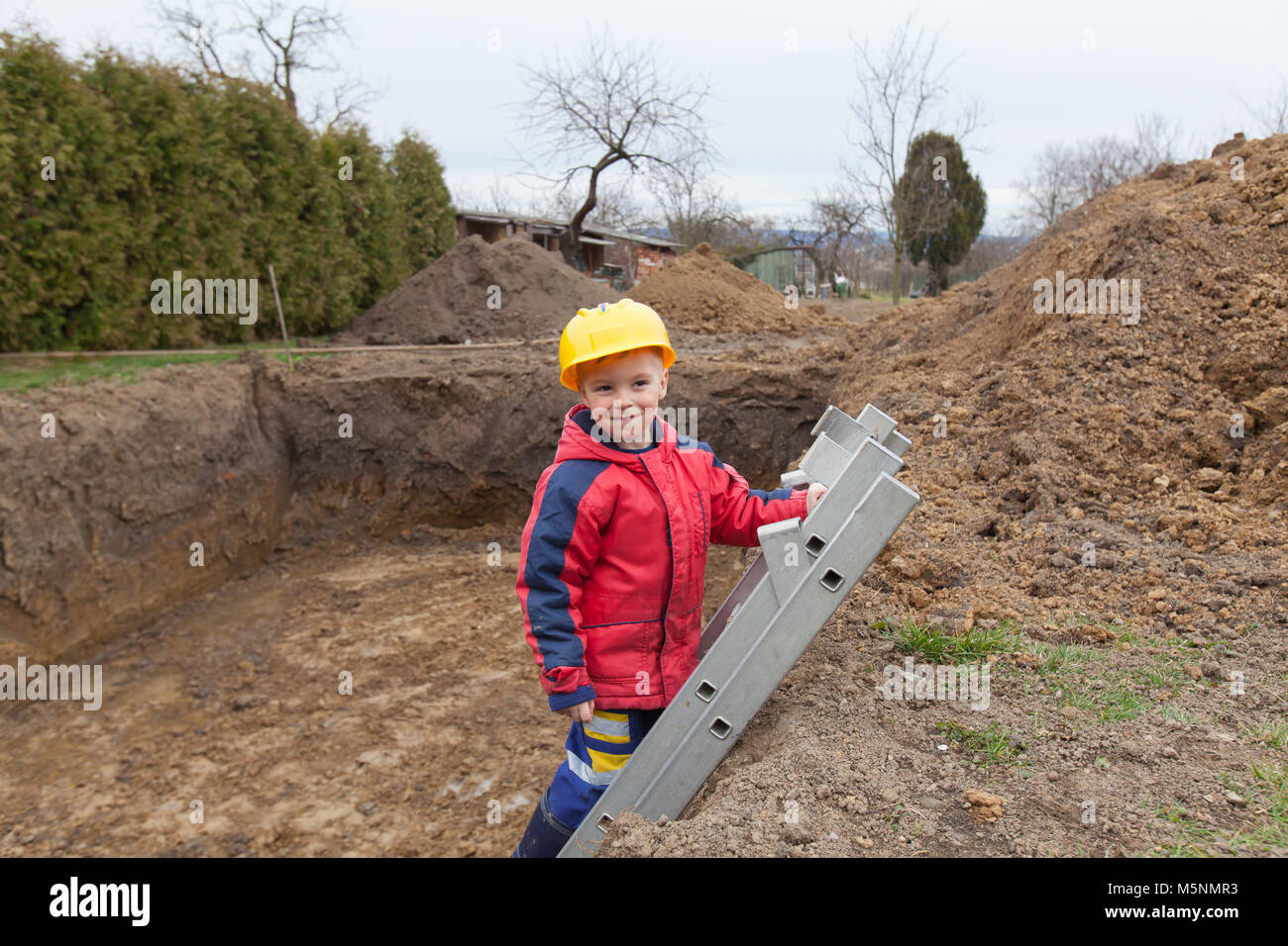 Little boy with a spade helps parents during the construction of the ...