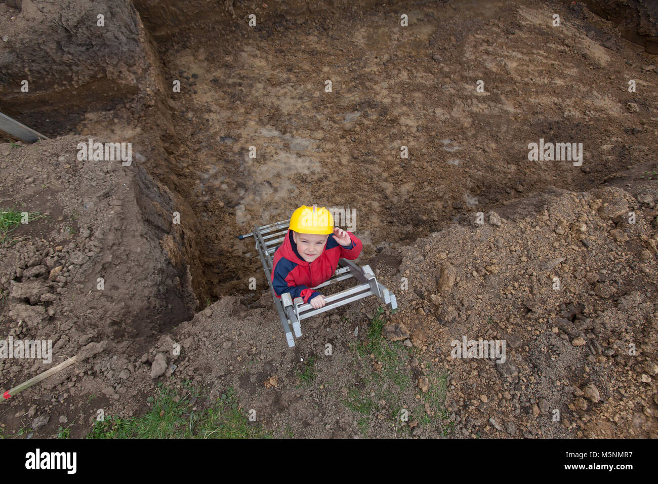 Little boy with a spade helps parents during the construction of the ...