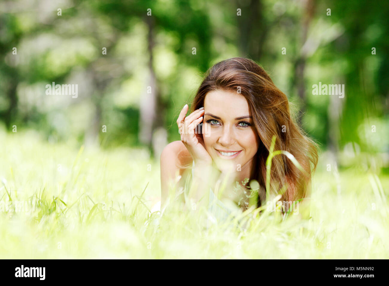 beautiful young woman in blue dress lying on grass Stock Photo - Alamy