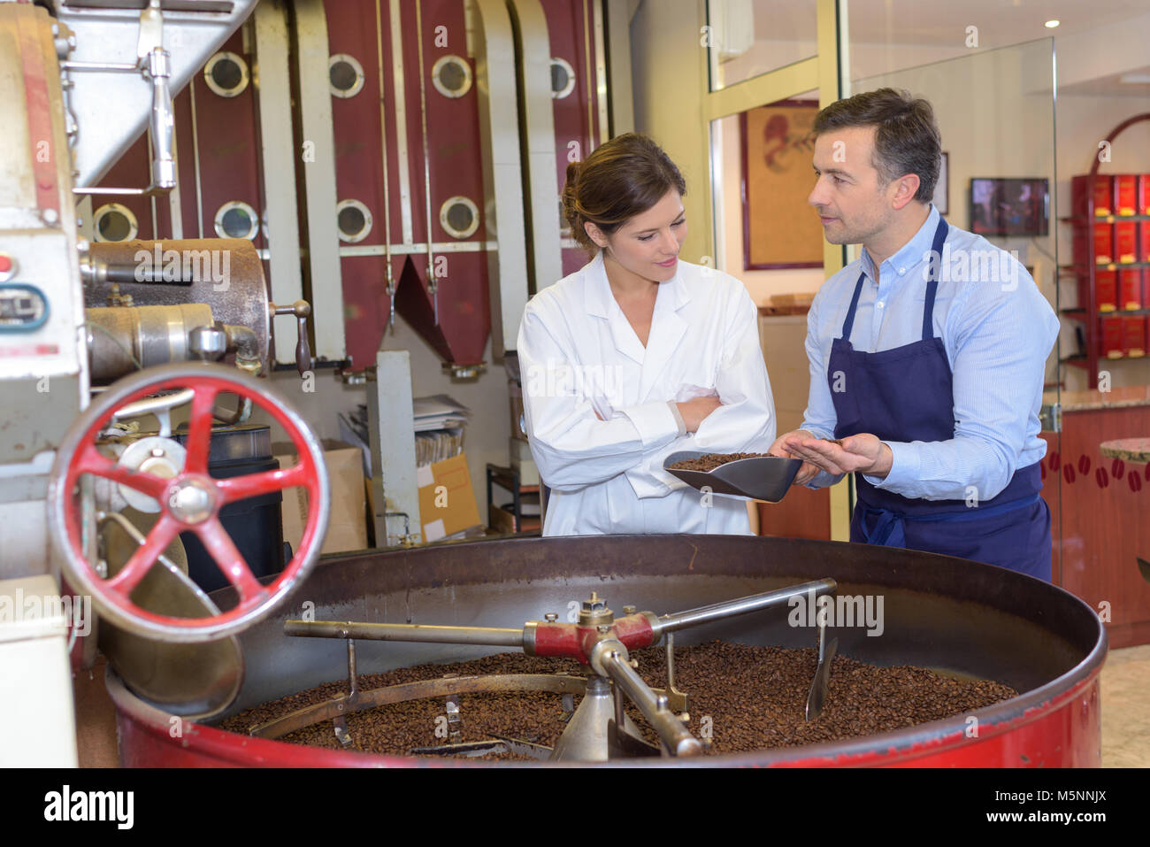 Man and woman stood over vat of coffee beans Stock Photo Alamy