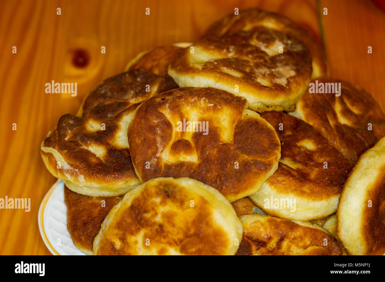 Russian pirozhki, fresh fried pasties stuffed with potatoes in a plate on a  wooden table Stock Photo - Alamy