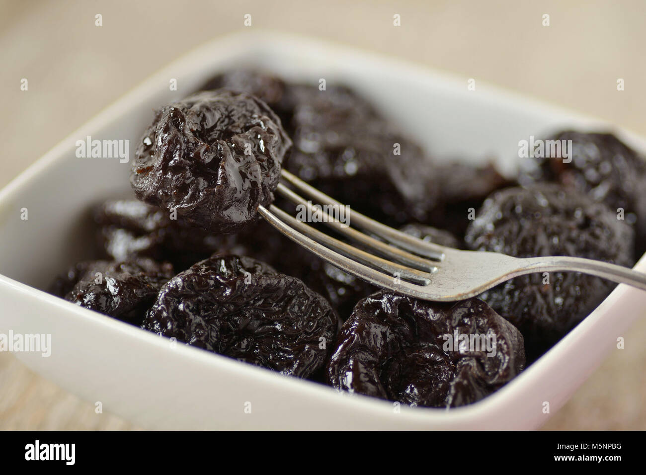 Dried prunes in a bowl with a fork Stock Photo Alamy