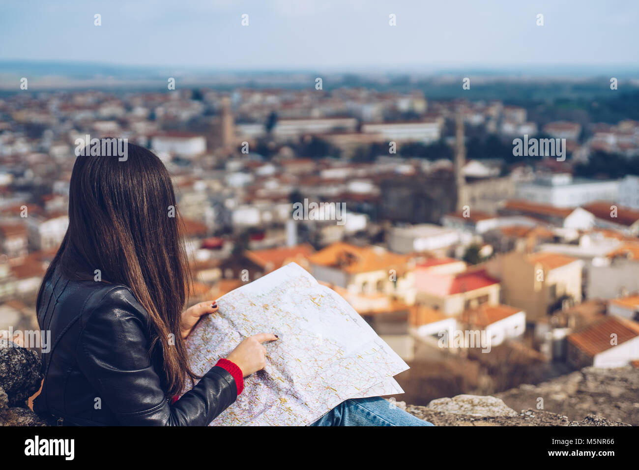 Young girl standing in front of beautiful city view and looking at the ...