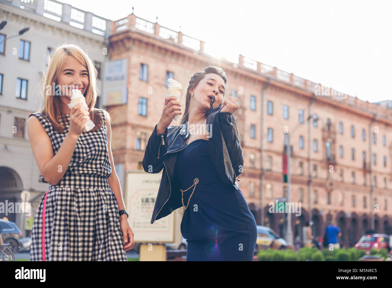 Two best friends having ice cream together outdoors. Young women eating