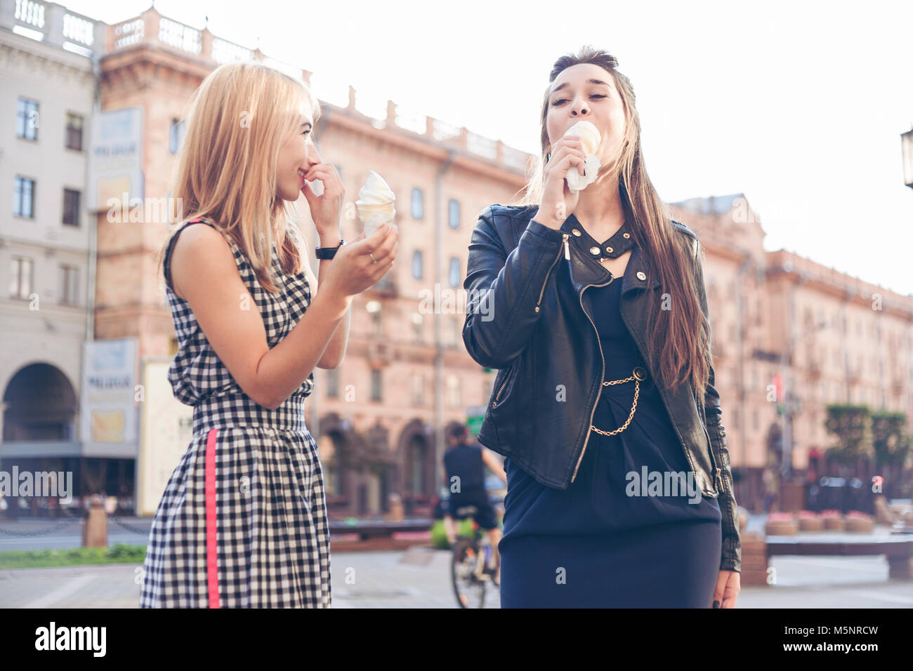 Two best friends having ice cream together outdoors. Young women eating