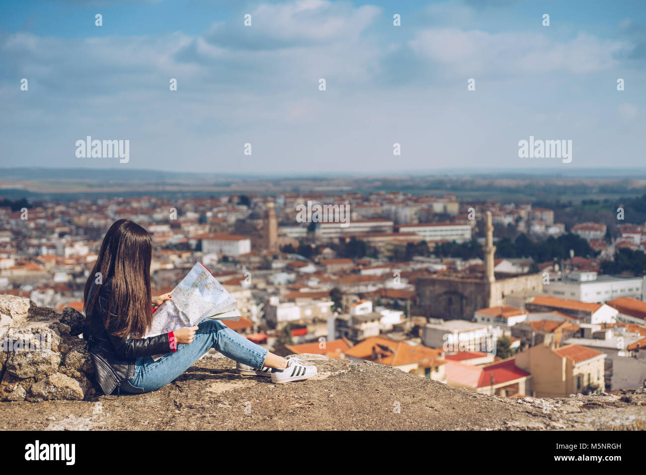 Young girl standing in front of beautiful city view and looking at the ...