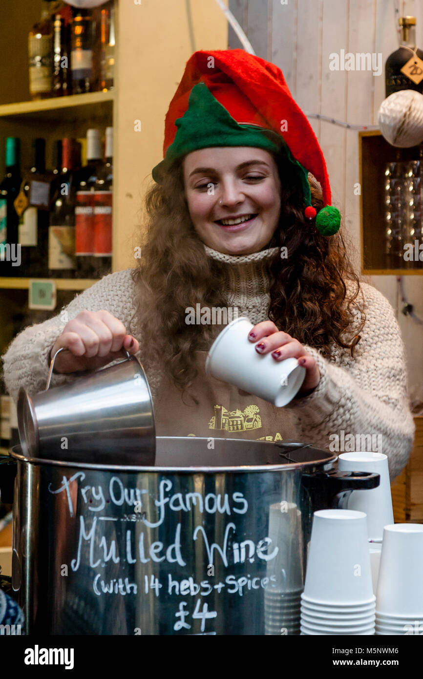 A Young Woman Selling Mulled Wine In Borough Market At Christmas Time, London, UK Stock Photo