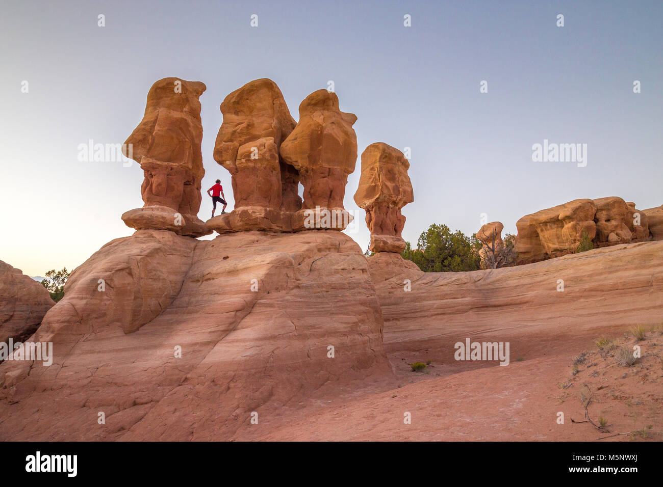 Hiker standing between hoodoos sandstone formations at sunset in Devil's Garden, Grand Staircase-Escalante National Monument, Utah USA Stock Photo