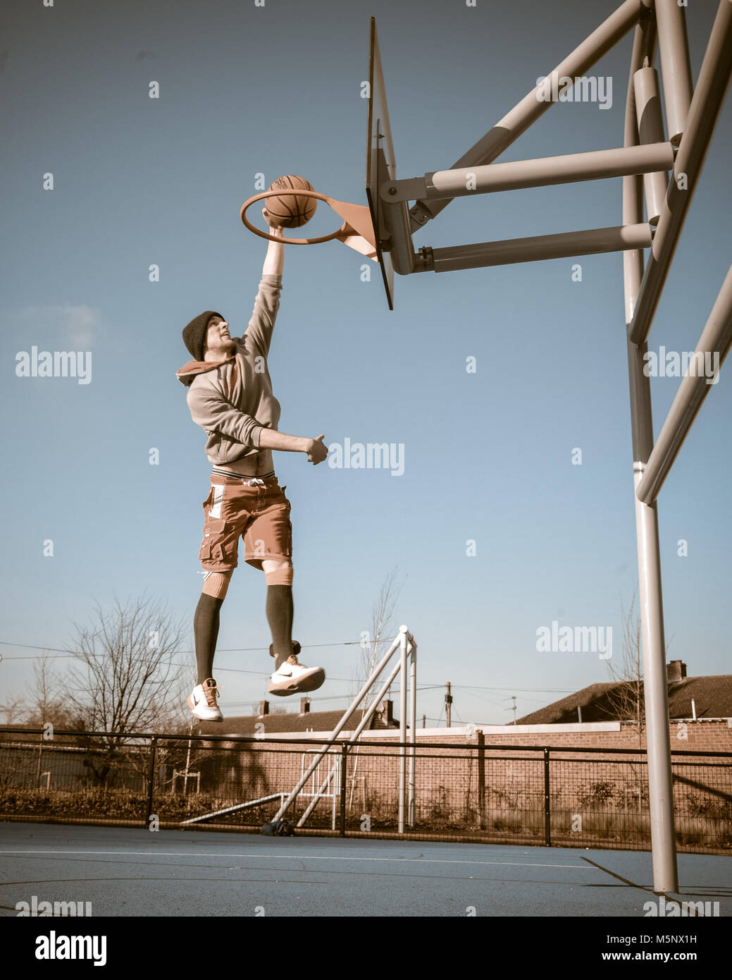 An outdoor shoot of a basketball player in Devizes, Wiltshire. Shot in natural sunlight on a basketball court. Wide depth of filed, good lighting. Stock Photo