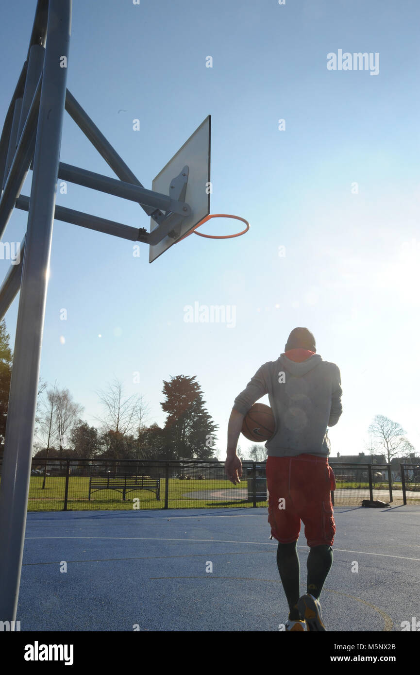 An outdoor shoot of a basketball player in Devizes, Wiltshire. Shot in natural sunlight on a basketball court. Wide depth of filed, good lighting. Stock Photo