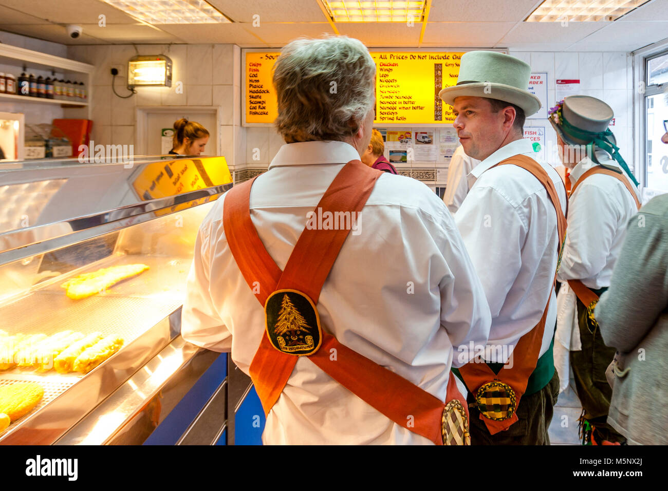 Morris Dancers Queue Up For Fish and Chips In A Lewes ‘Chippie’ Between Performances At The Lewes Folk Festival, Lewes, Sussex, UK Stock Photo