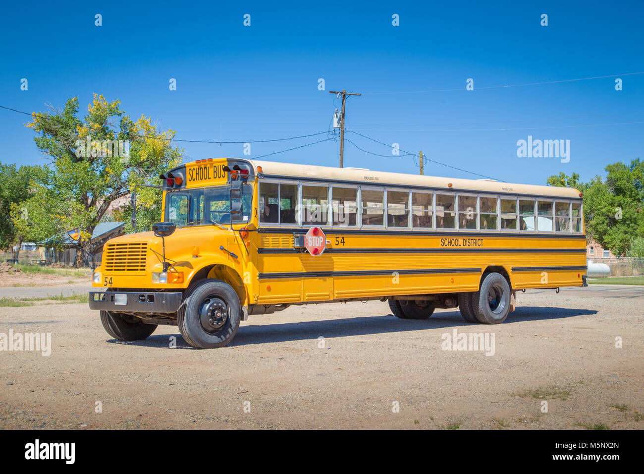 Panorama view of classic tradtional yellow school bus standing on a parking lot on a beautiful sunny day with blue sky in summer in North America Stock Photo