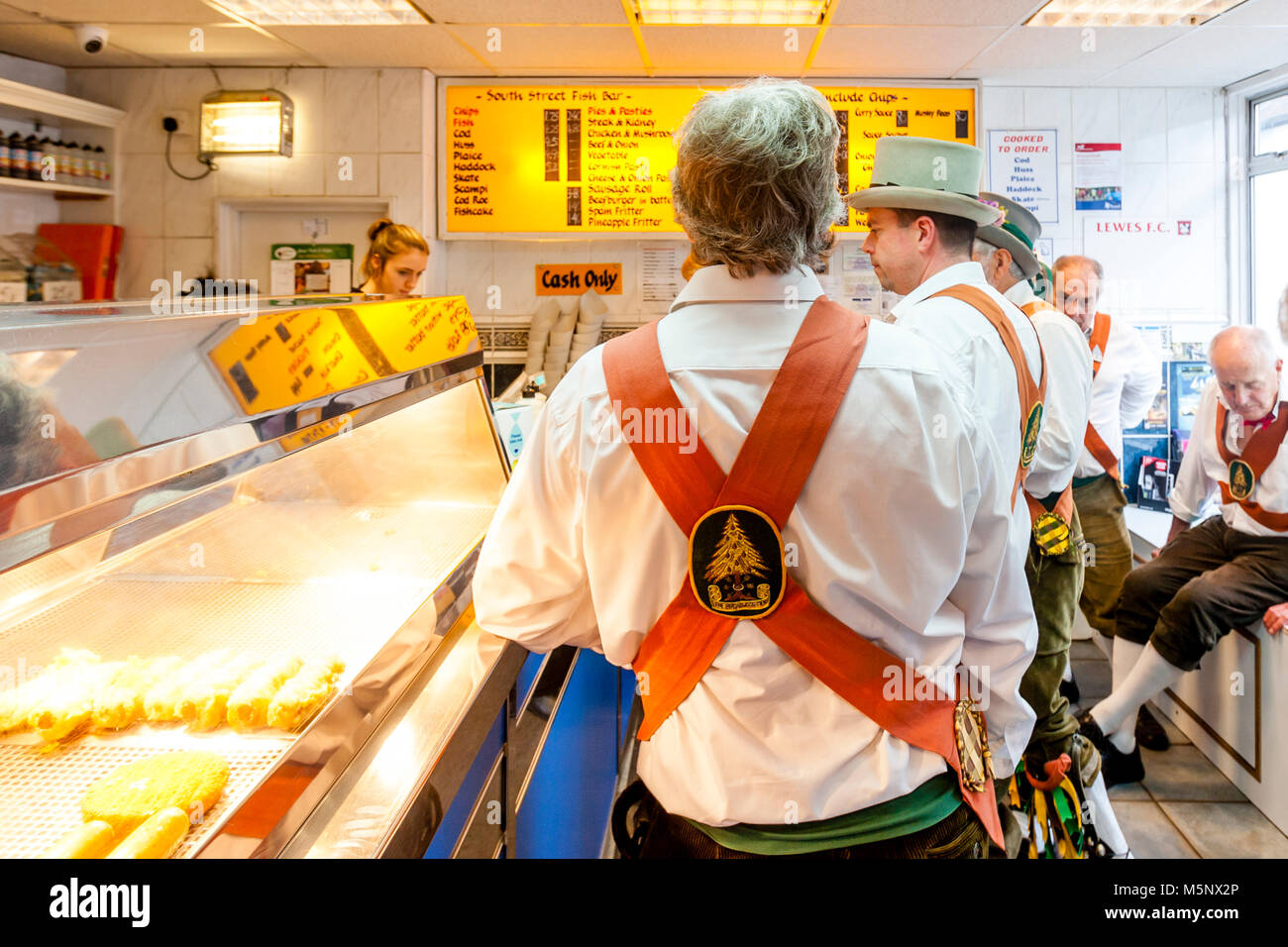 Morris Dancers Queue Up For Fish and Chips In A Lewes ‘Chippie’ Between Performances At The Lewes Folk Festival, Lewes, Sussex, UK Stock Photo