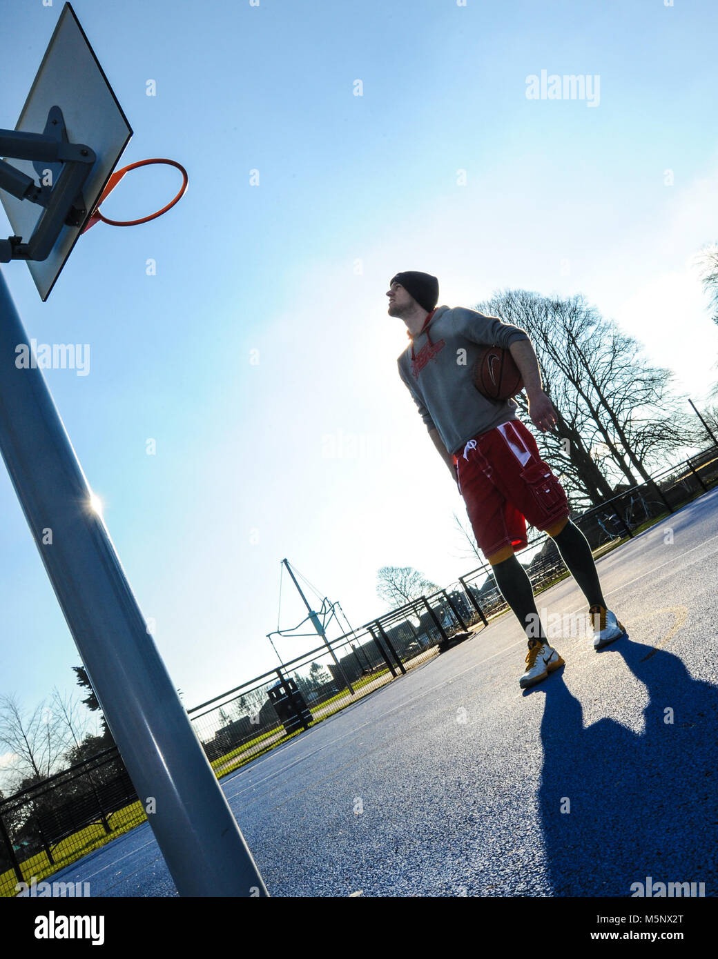 An outdoor shoot of a basketball player in Devizes, Wiltshire. Shot in natural sunlight on a basketball court. Wide depth of filed, good lighting. Stock Photo