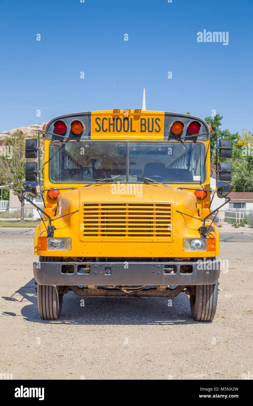 Frontal view of classic tradtional yellow school bus standing on a parking lot on a beautiful sunny day with blue sky in summer in North America Stock Photo