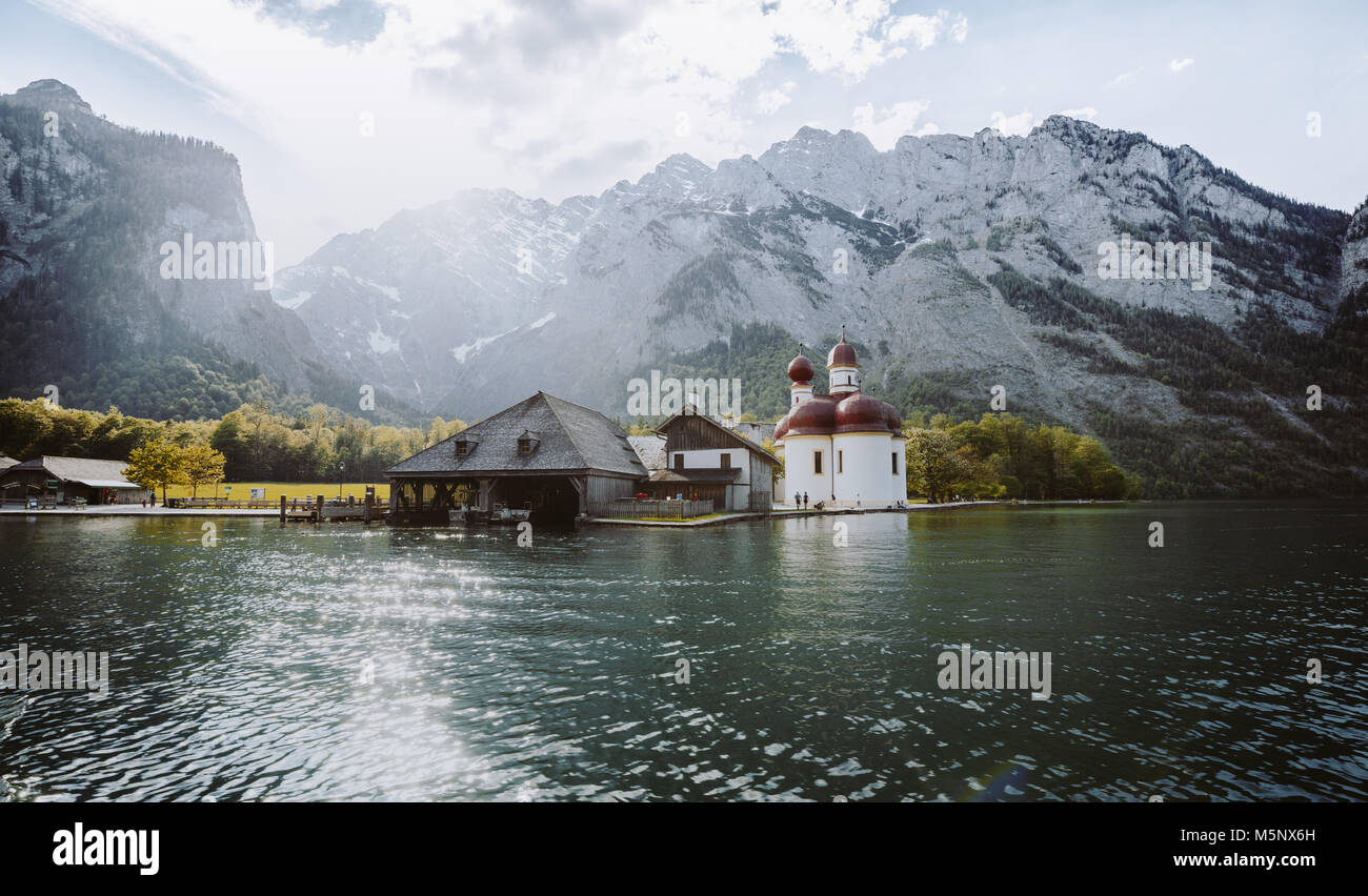 Classic panoramic view of Lake Konigssee with world famous Sankt Bartholomae pilgrimage church and Watzmann mountain in beautiful golden evening light Stock Photo