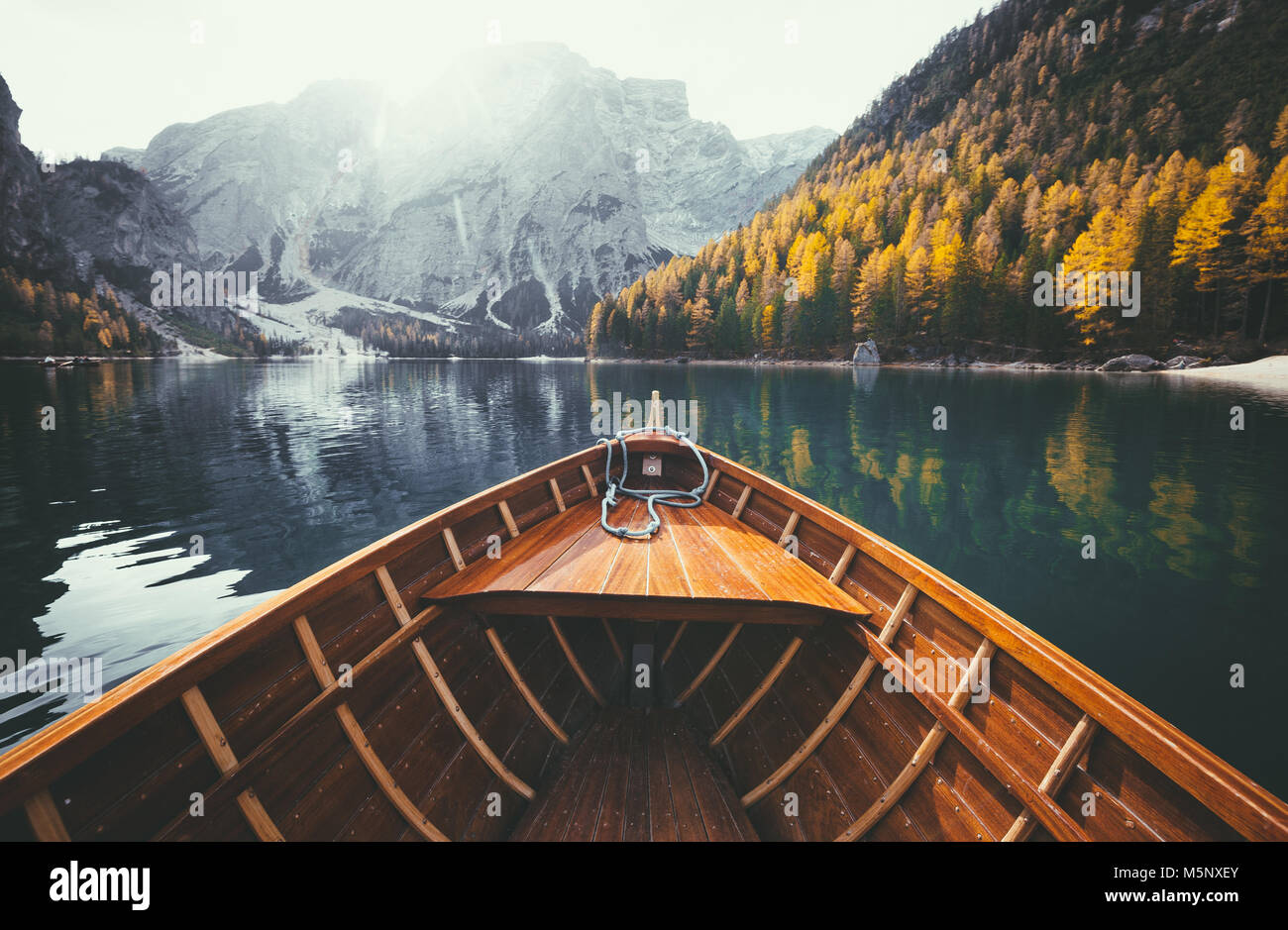 Scenic view of traditional wooden rowing boat gliding on famous Lago di Braies in the Italian Dolomites on a beautiful sunny day in fall with retro vi Stock Photo