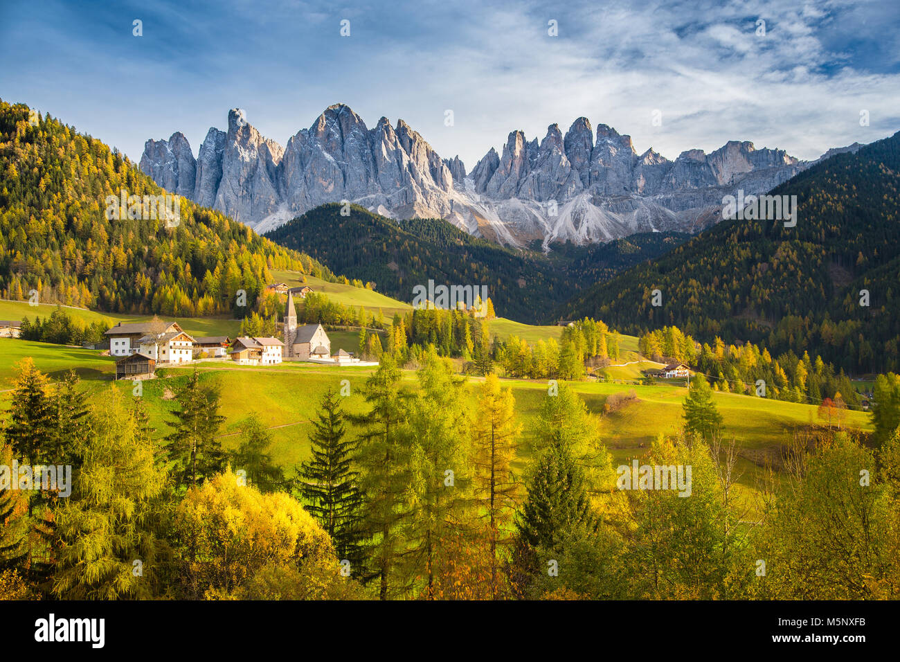 Idyllic mountain scenery in the Dolomites with Santa Maddelana mountain village in beautiful golden evening light at sunset, South Tyrol, Italy Stock Photo