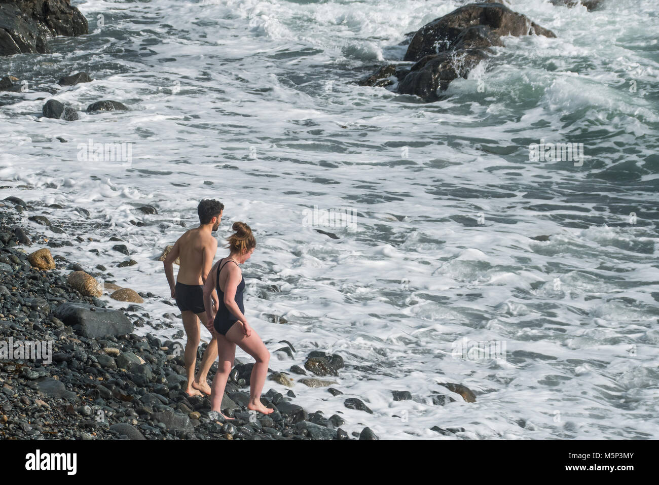 Mousehole, Cornwall, UK. 25th Feb 2018. UK Weather. Sunday was a freezing cold day in Cornwall, with strong winds from the 'beast in the east'. Neverthless this hardy couple decided to strip off and go for a invigorating paddle in the sea. Credit: cwallpix/Alamy Live News Stock Photo