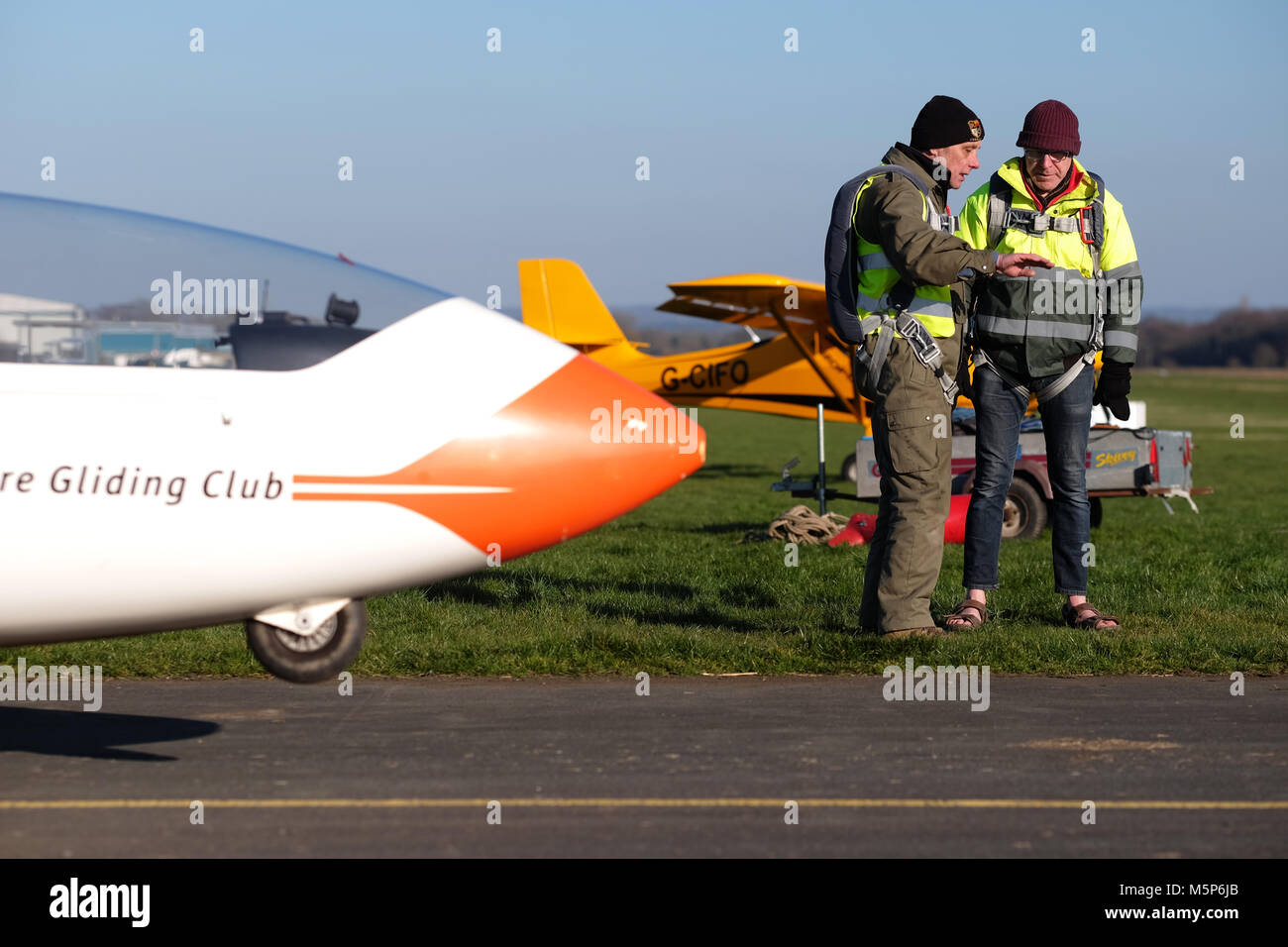 Shobdon airfield, Herefordshire - Sunday 25th February 2018 - Glider instructor and student pilot discuss the next flight on a bright sunny but very cold day at Shobdon airfield. Local temperatures reached only 4c but a bitterly cold easterly wind made it feel freezing.  Photo Steven May / Alamy Live News Stock Photo