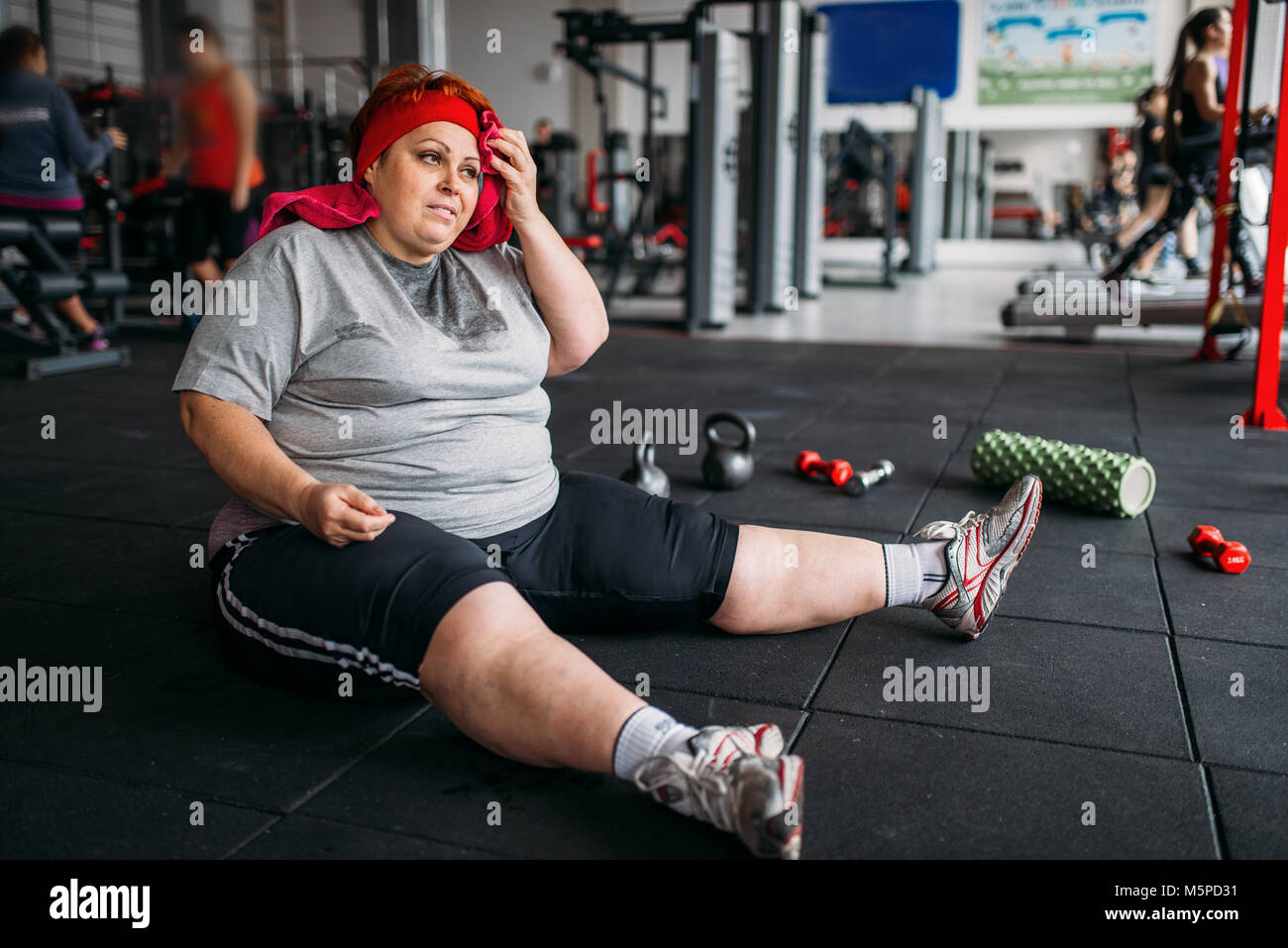 Tired fat woman sits on the floor in gym. Calories burning, obese female  person in sport club Stock Photo - Alamy