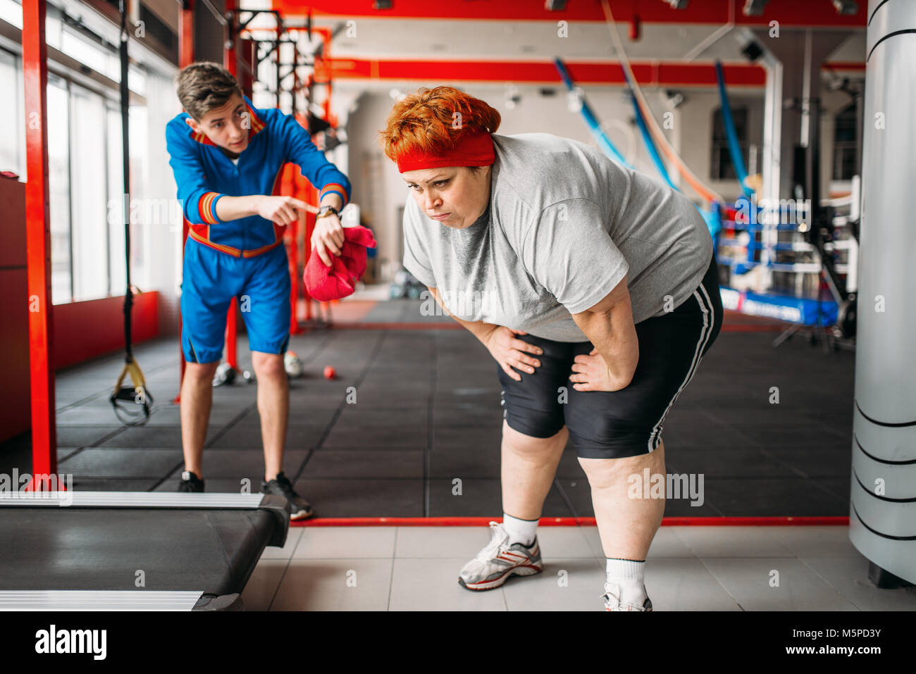 Instructor forces fat woman to exercise, hard workout in gym. Calories