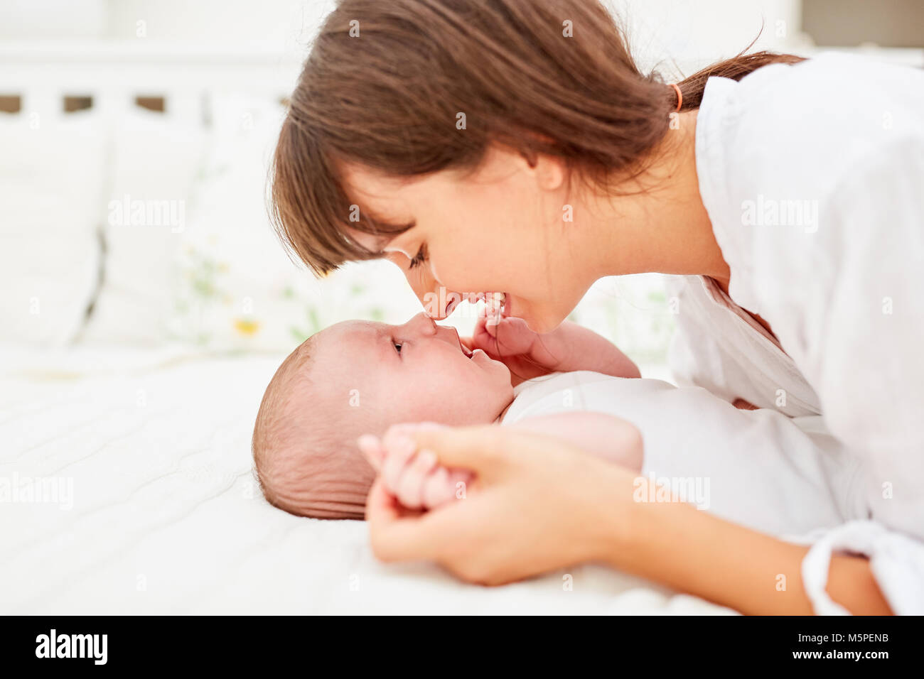 Young woman as a happy mother cuddles with her newborn baby Stock Photo