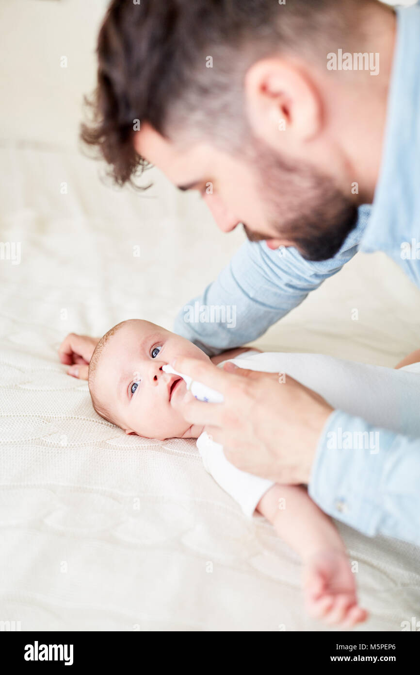 Caring father gives newborn baby nasal spray for runny nose Stock Photo