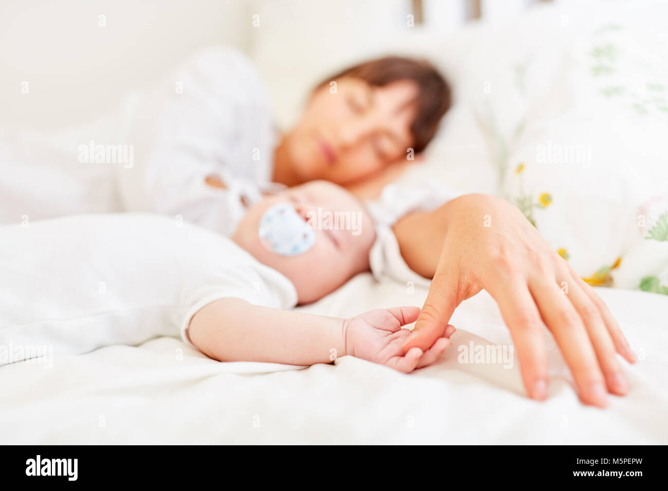 Big hand of mother and little hand of the baby are touching each other in sleep Stock Photo