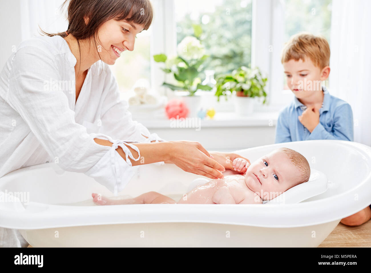 Caring mother bathes her newborn baby in the bath in the bath Stock