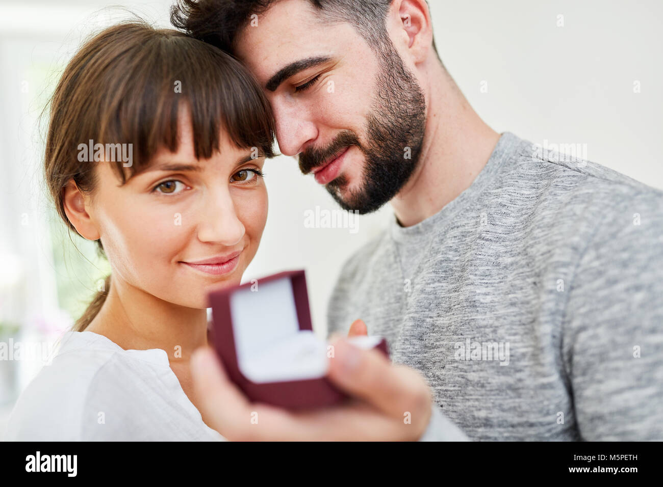 Young man with wedding rings in a box makes a declaration of love to woman Stock Photo