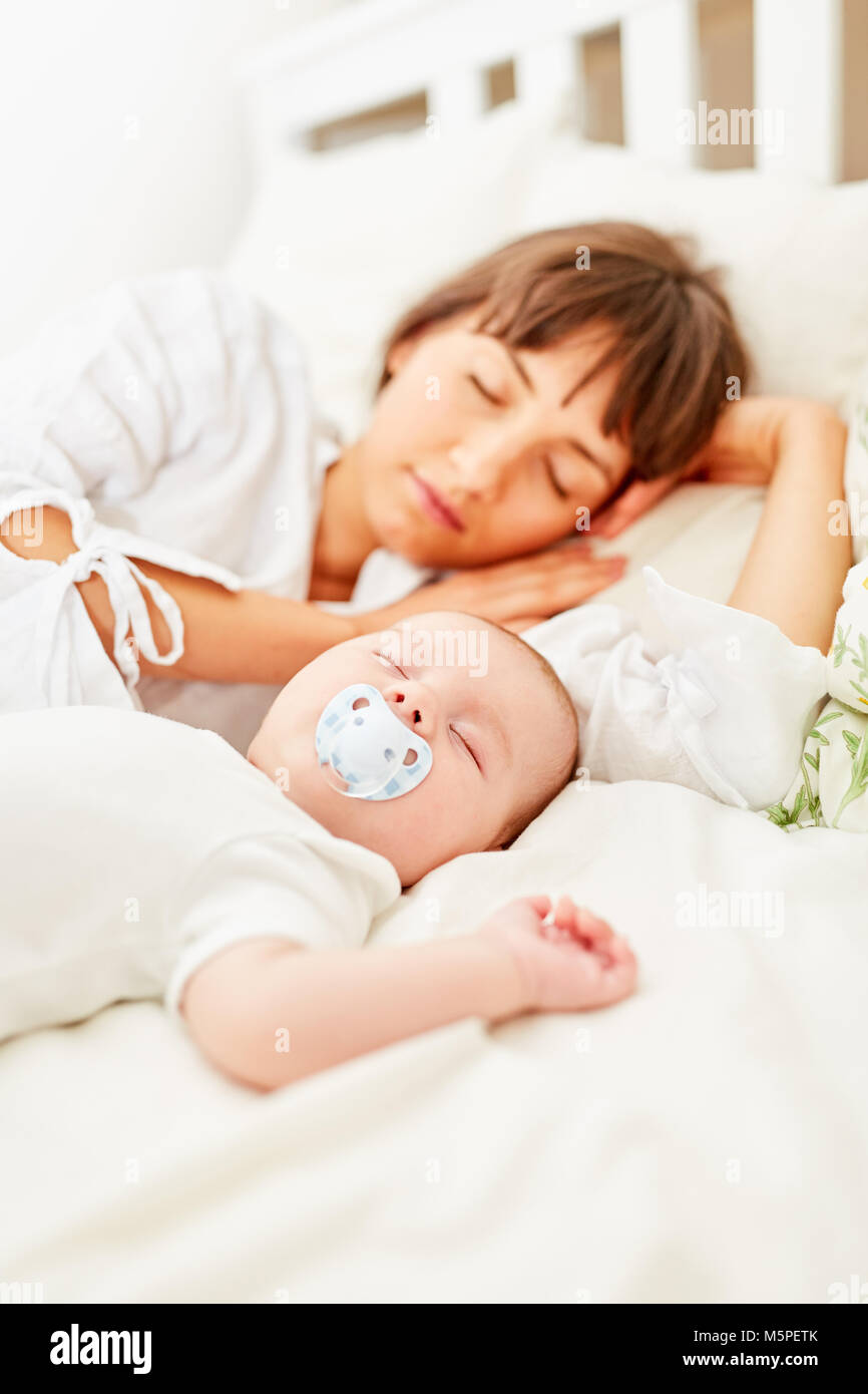 Mother sleeps after birth exhausted on the bed with her baby Stock Photo
