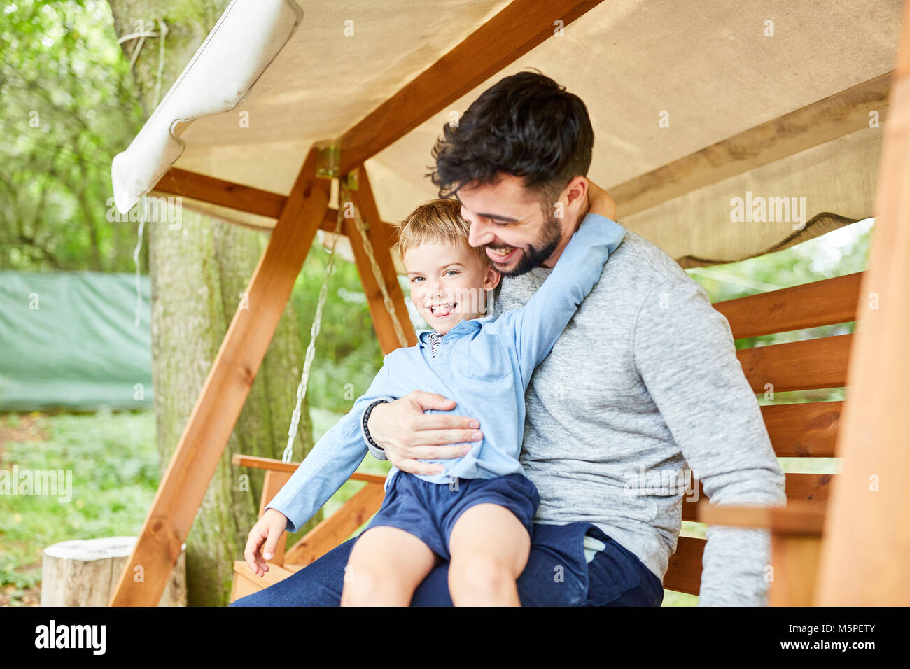Father and son are silly with each other on the garden swing in the garden Stock Photo