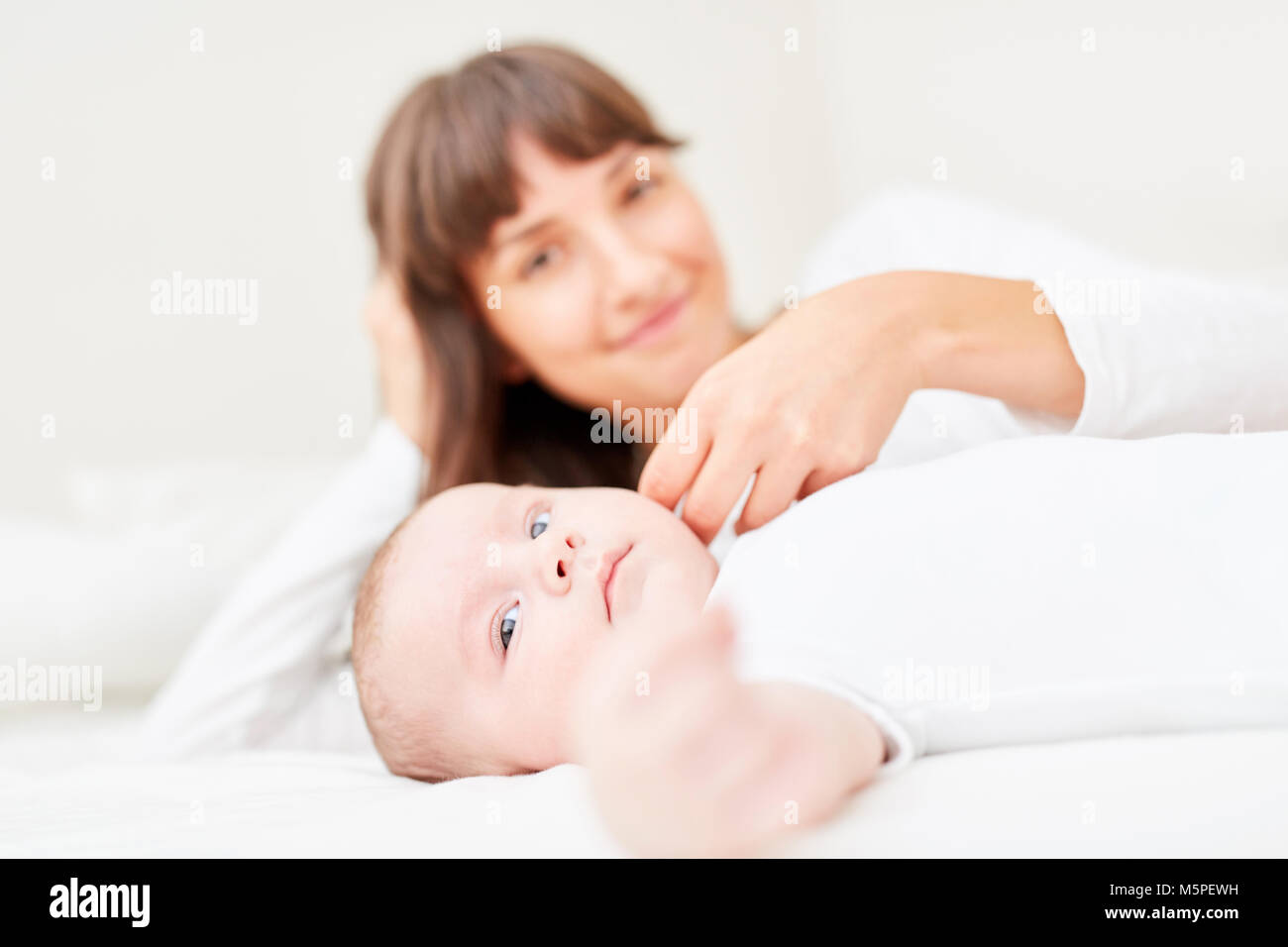 Loving mother caresses the cheek of her baby tenderly at home Stock Photo