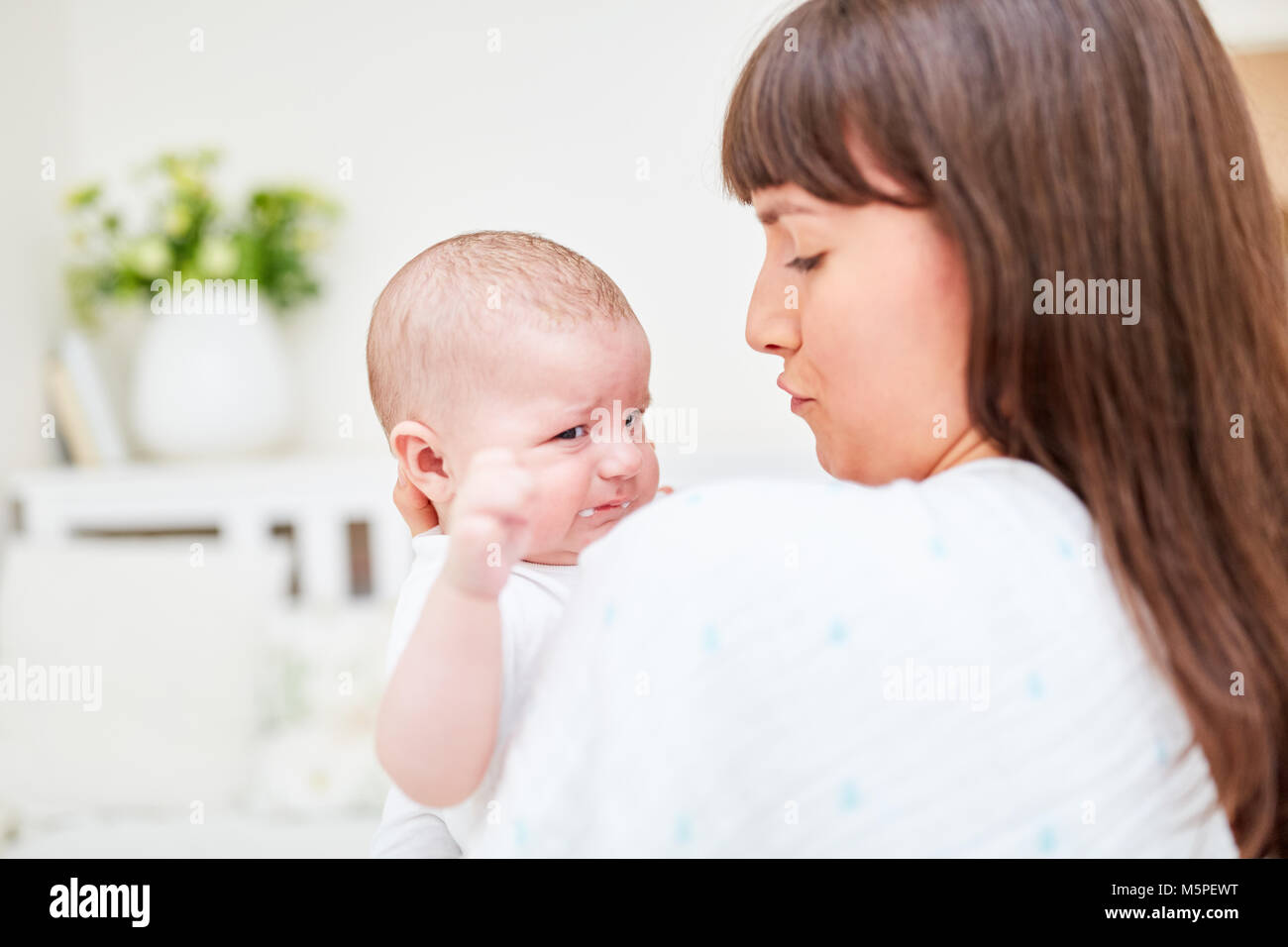 Young woman as happy and loving mother consoles her little baby Stock Photo