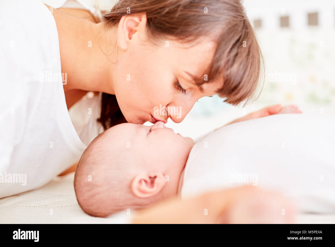 Young happy mother gives her baby a tender kiss on the forehead Stock Photo