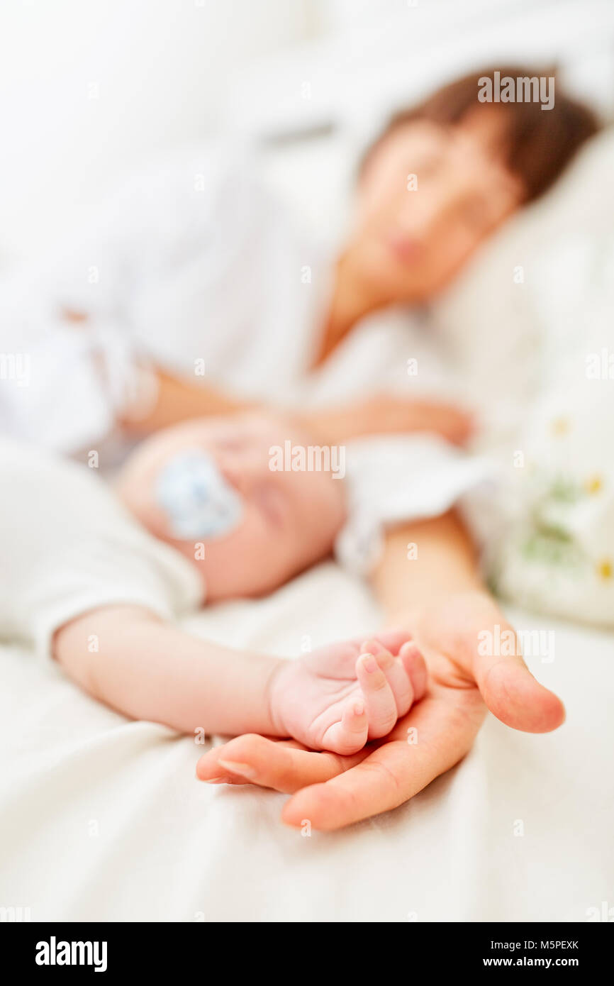 Mother and baby are sleeping peacefully and peacefully hand in hand on the bed Stock Photo