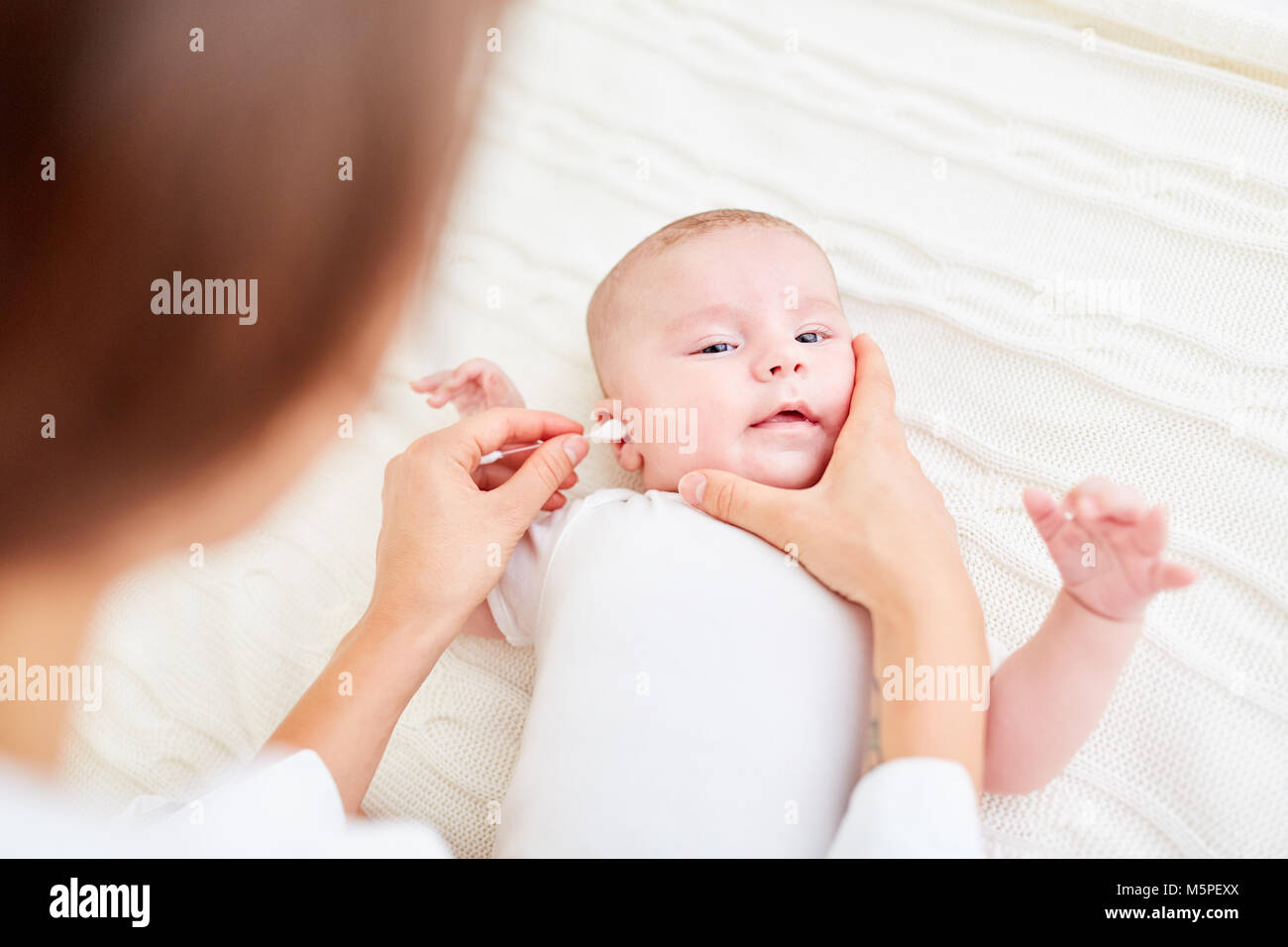 Baby care mom cleans baby's ears with a cotton swab Stock Photo
